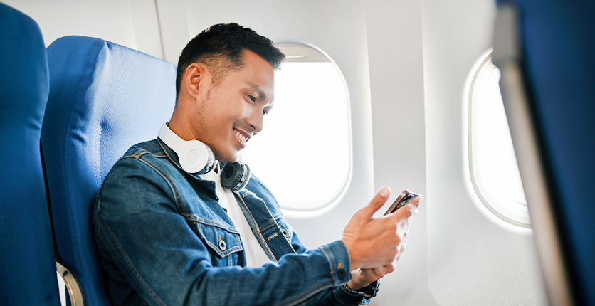 Young man looking at his mobile phone on a plane