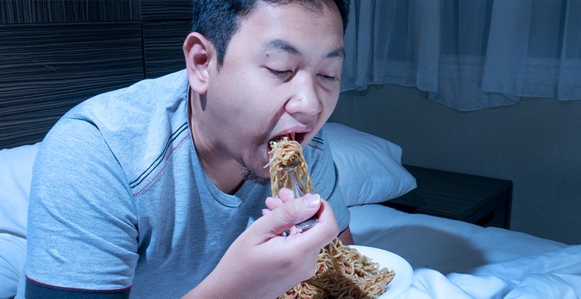 Man binging on fried food in bed