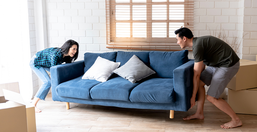 Couple moving a new sofa in their home