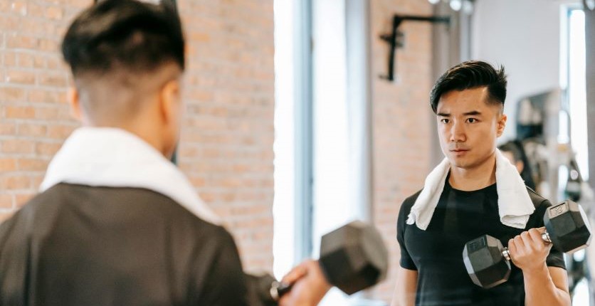 Man lifting weight while looking in mirror